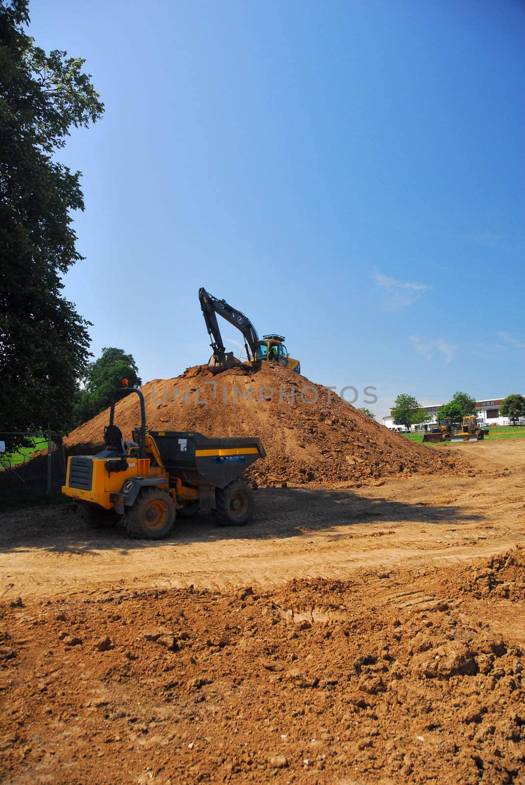 Two heavy machines moving and reshaping the spoil heap.