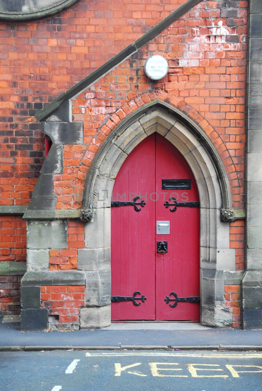 Old red, wooden doors built in gothic arch.