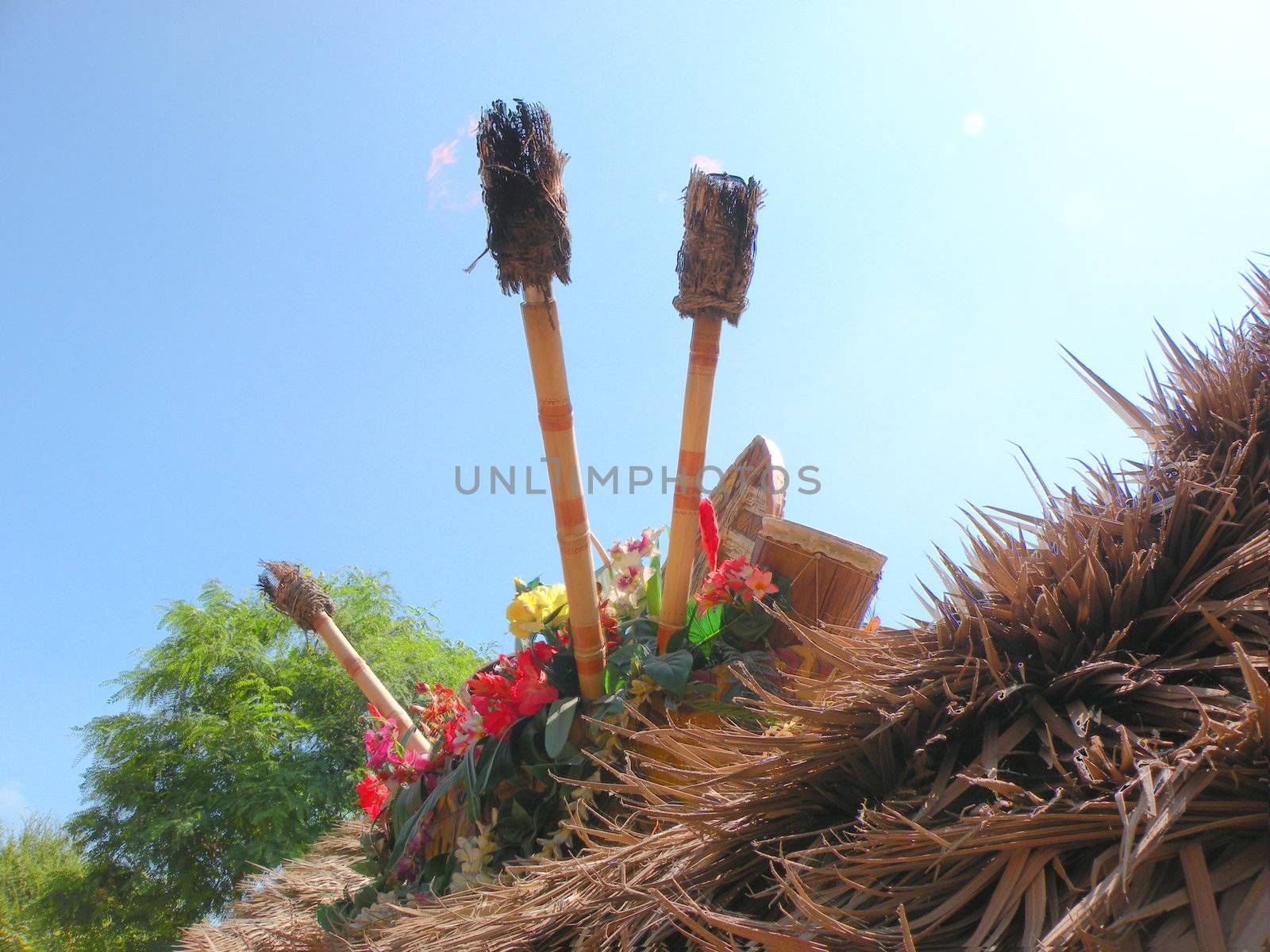 tiki torches no the top of a hut, ringed by flowers.