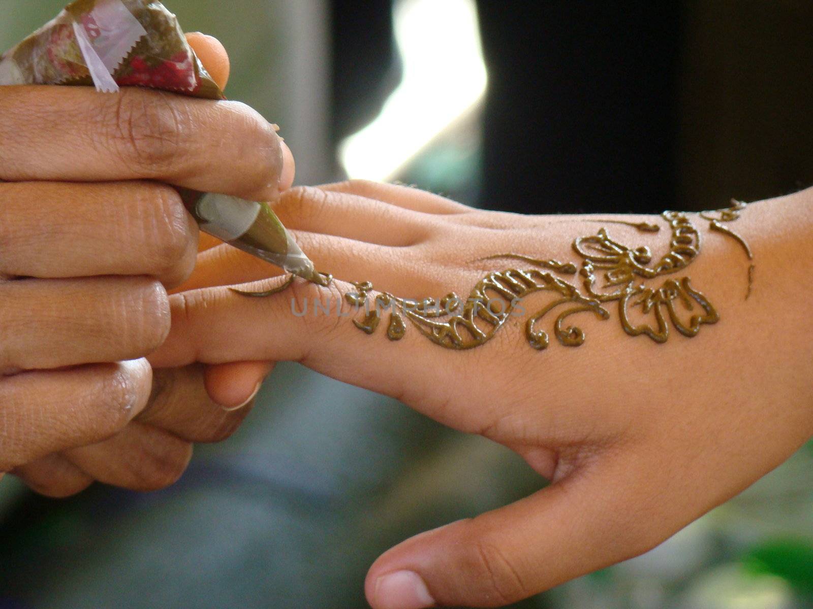 appling henna tattoo to hands by hicster