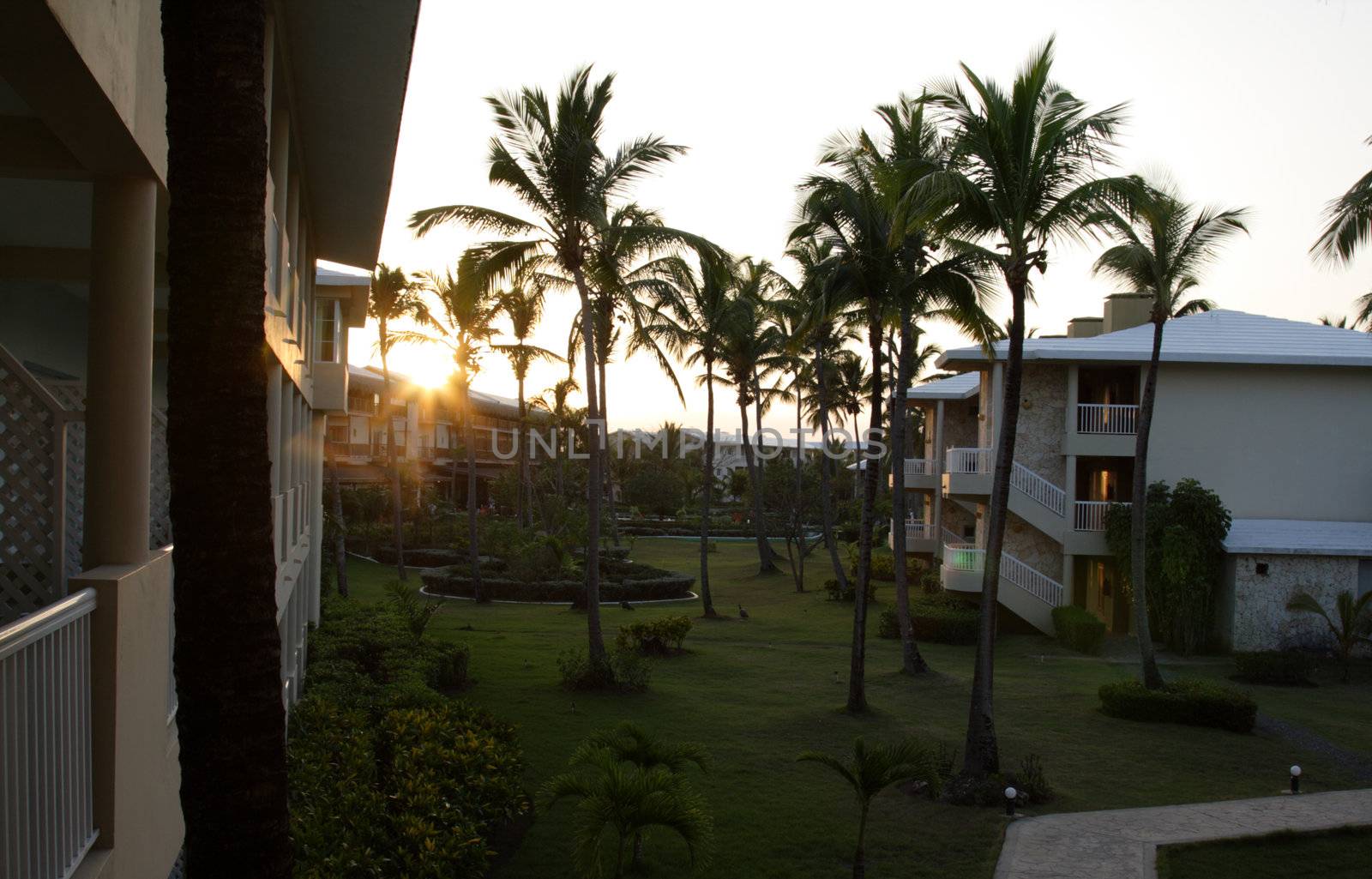 A tropical resort shot at dusk, with the sun dipping below the horizon.