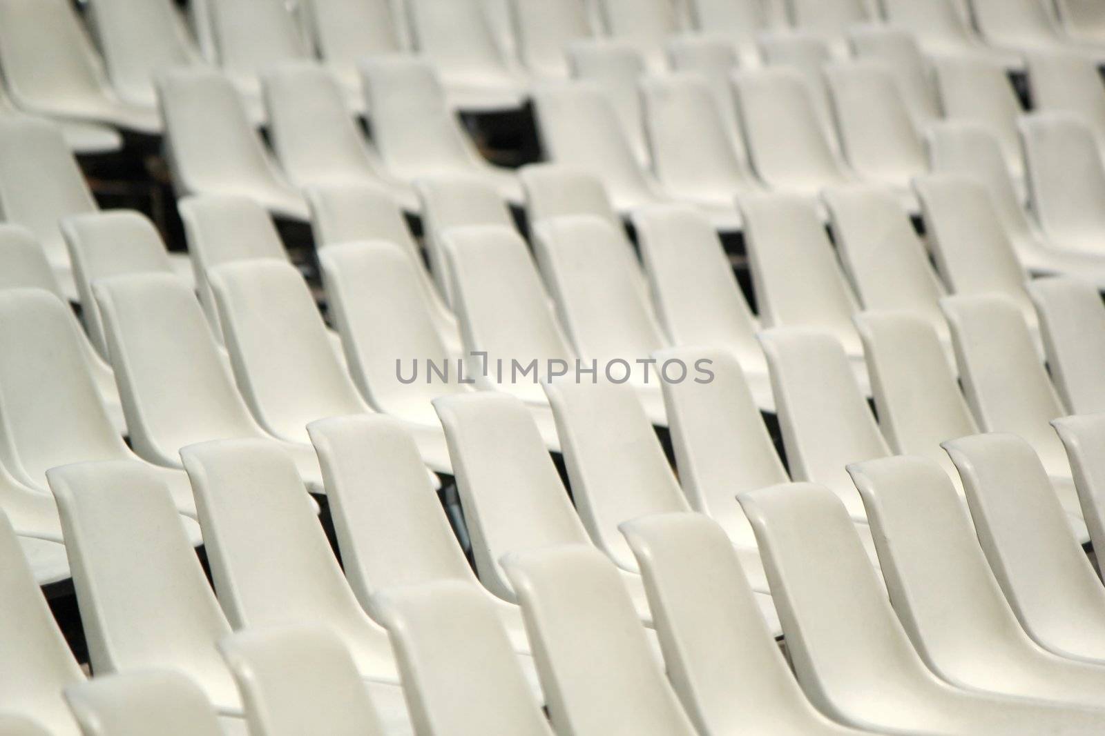 Lots of empty white plastic chairs aligned outdoor for a show
