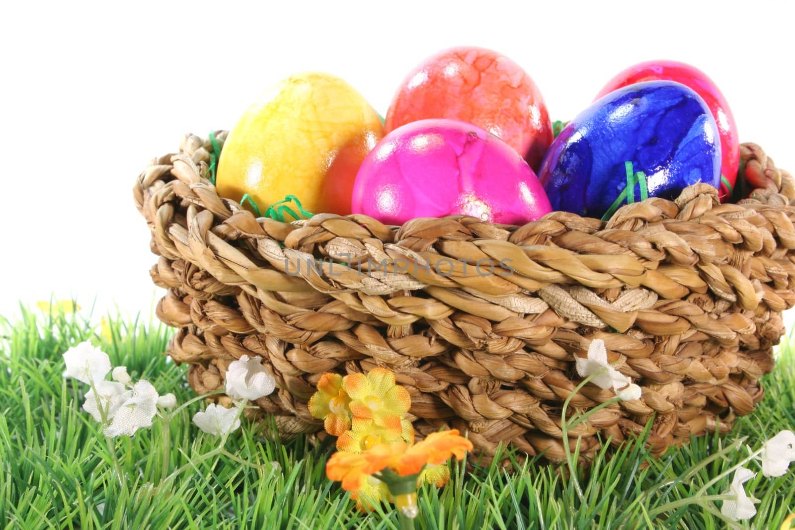 Easter basket with colorful Easter eggs on a green meadow
