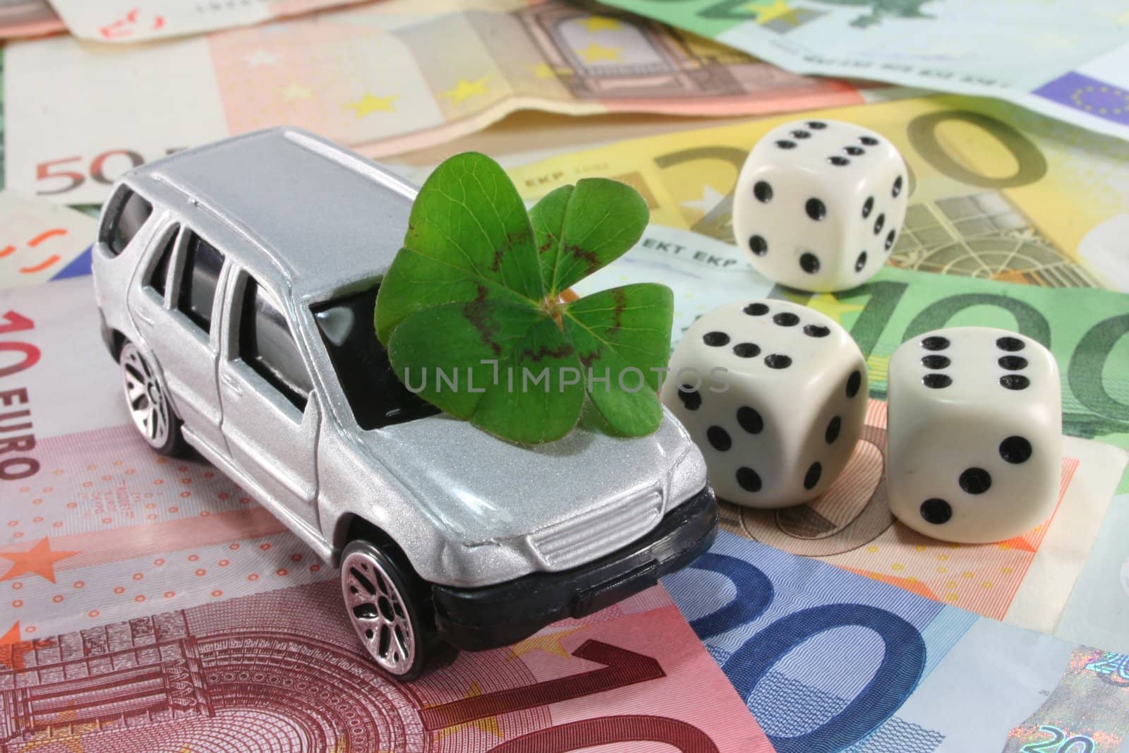 silver car with lucky clover, dice and Euro notes