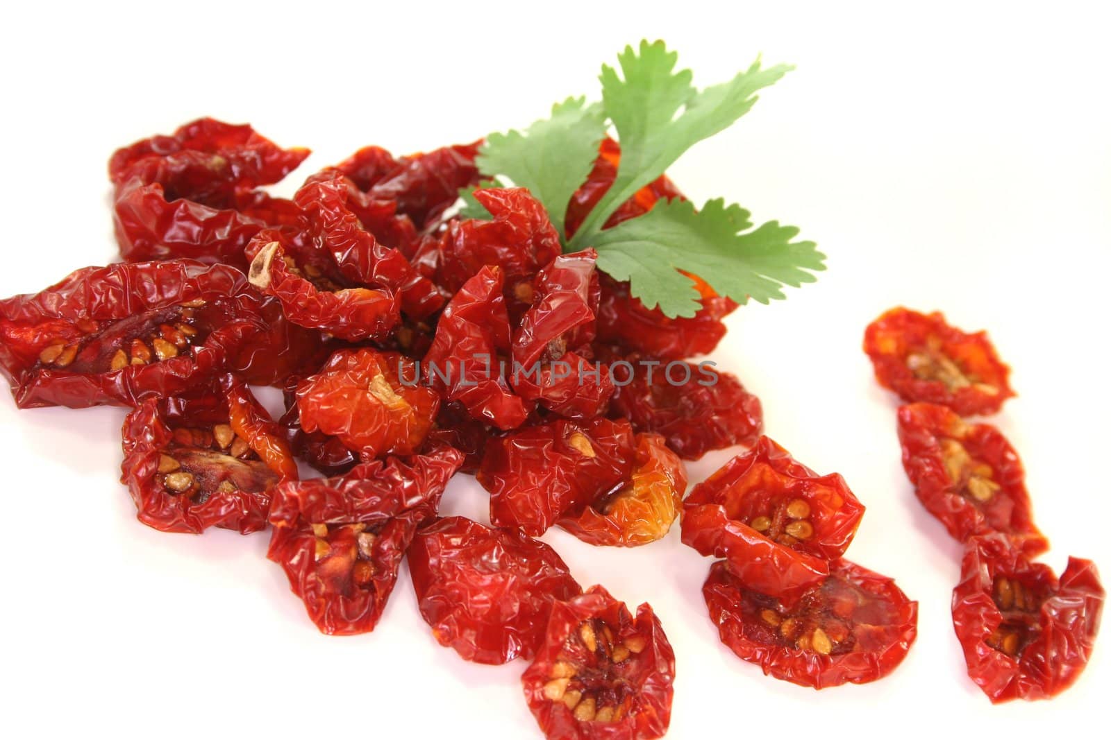 fresh dried tomatoes with a cilantro leaf on white background