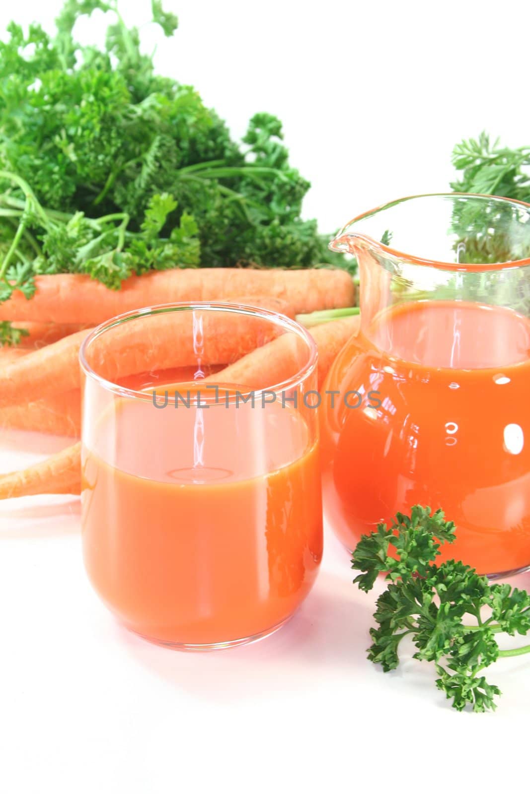 fresh carrot juice with a bunch of carrots and parsley