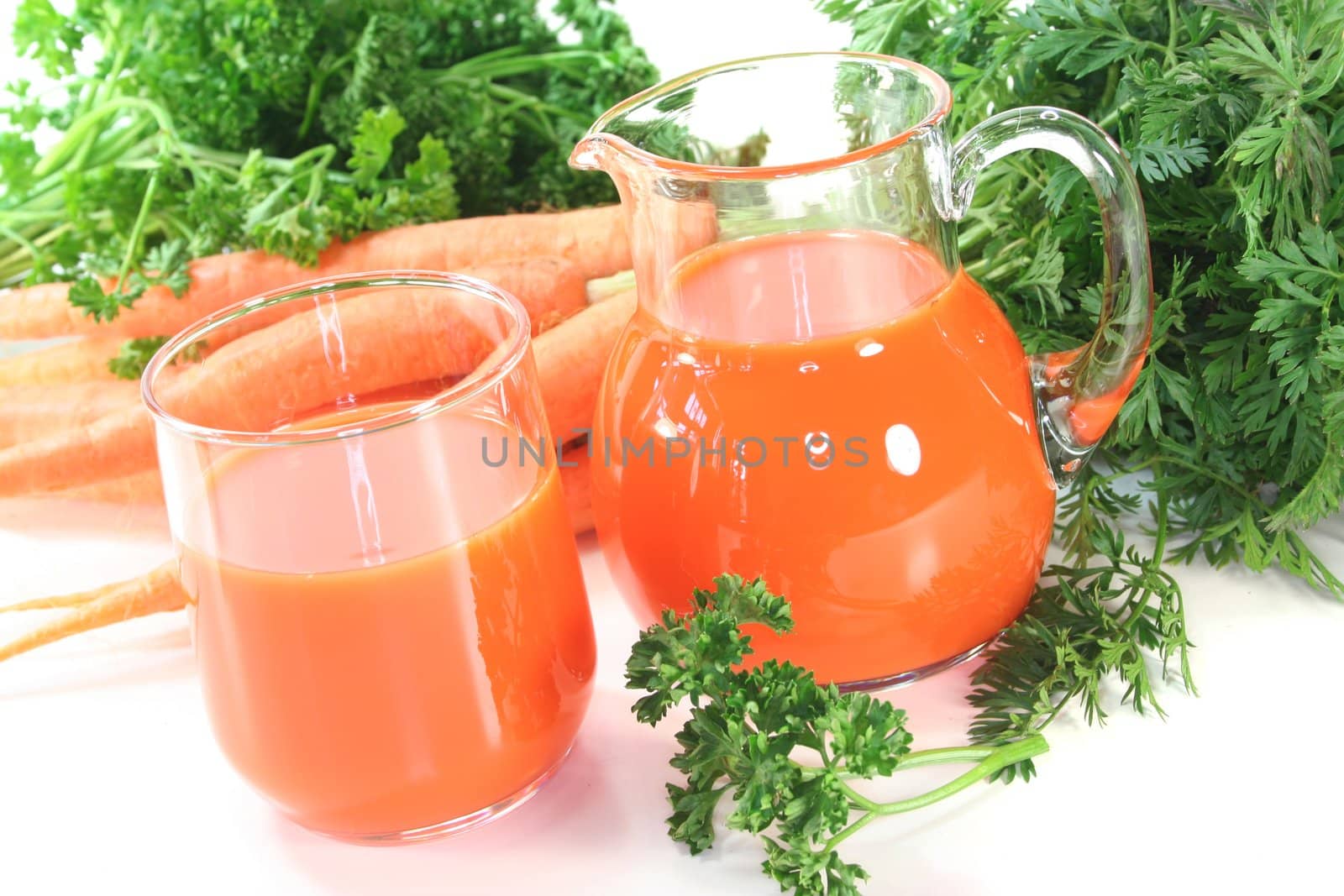 fresh carrot juice with a bunch of carrots and parsley