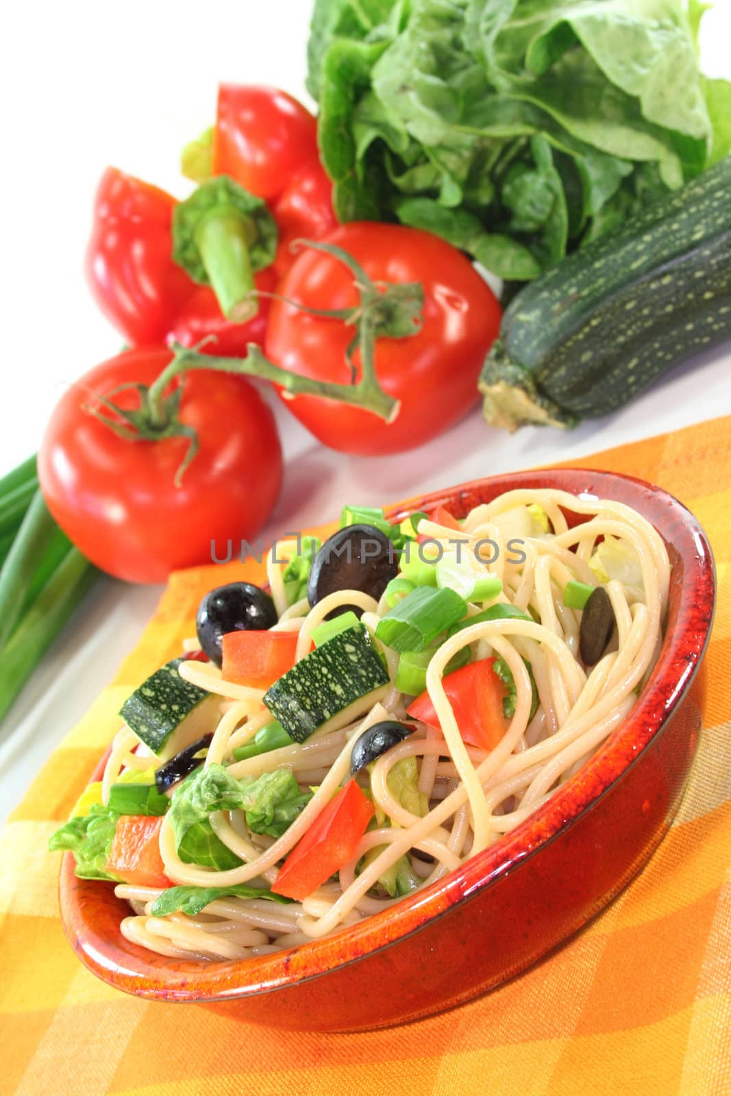a bowl of pasta salad with spaghetti and fresh vegetables