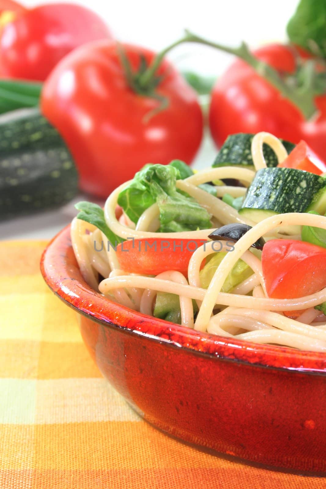 a bowl of pasta salad with spaghetti and fresh vegetables