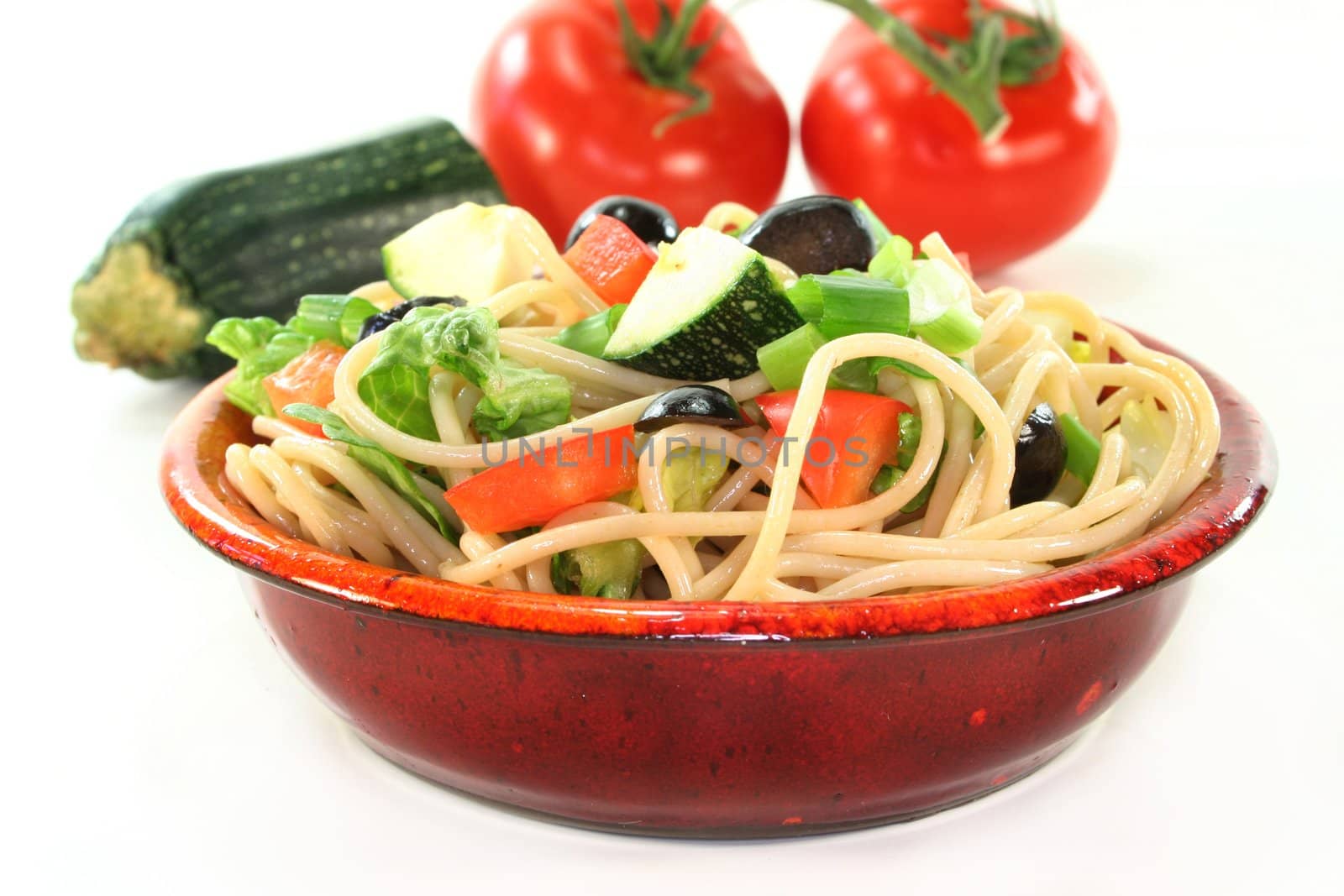 a bowl of pasta salad with spaghetti and fresh vegetables