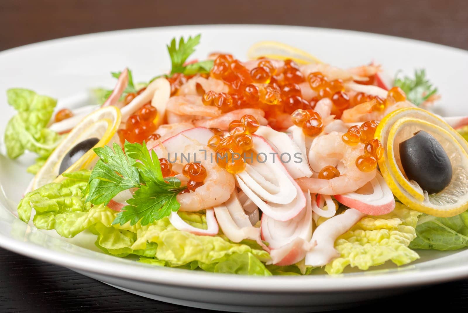 Salad with shrimps, caviar, calamaries, lettuce, lemon and olive