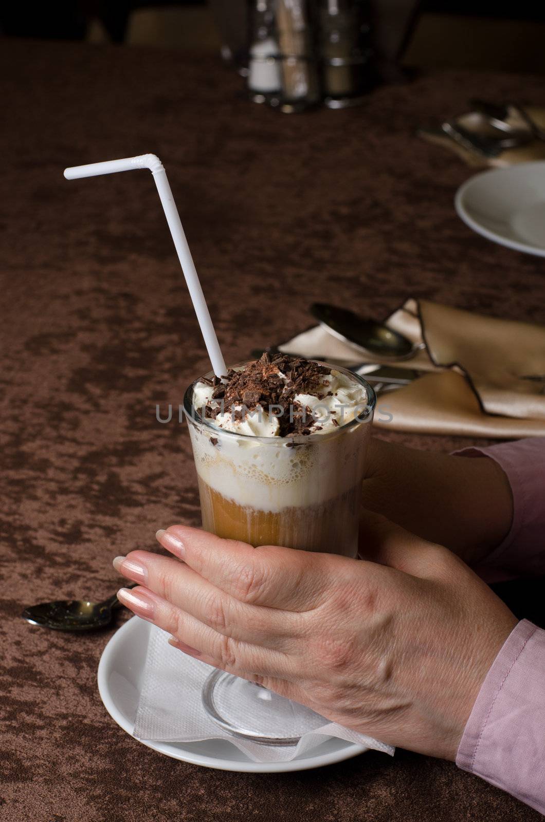 Closeup of female hands holding cup of latte