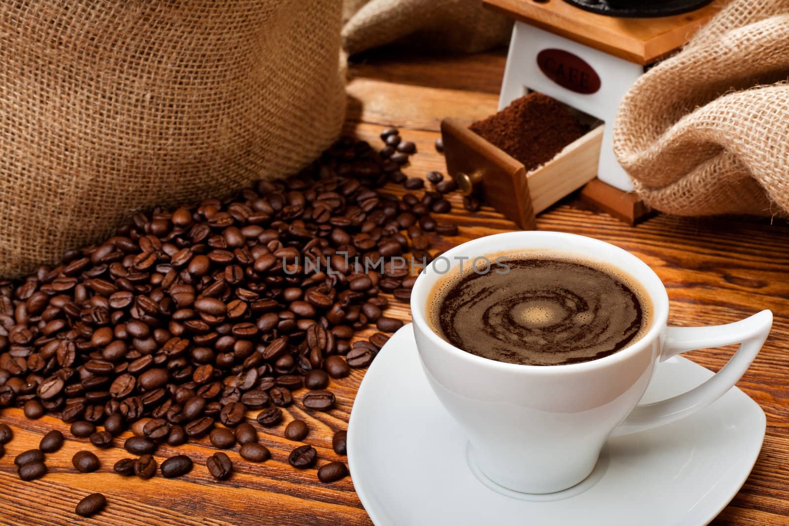 Studio photo of sack with scattered coffee grain, and cup of espresso