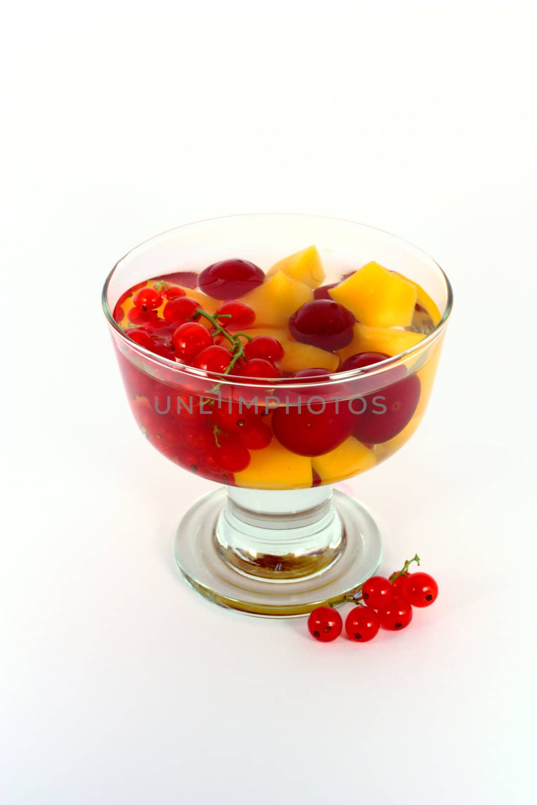Peach compote with fresh red currants in glass bowl isolated on white