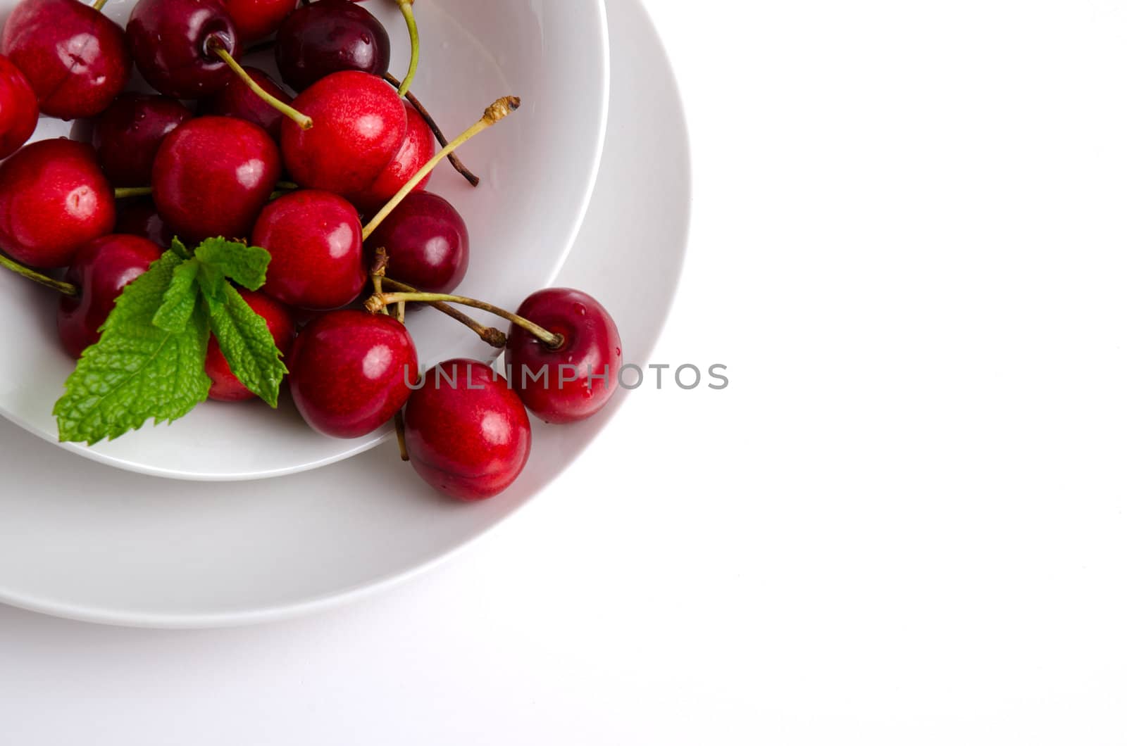 Red fresh cherries on plate background.