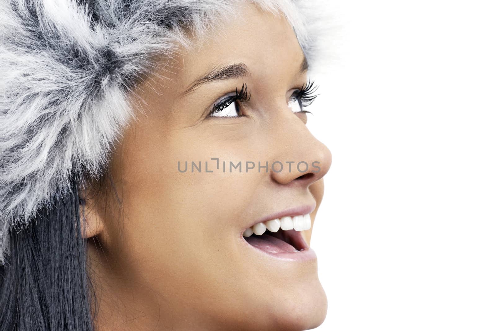 Fun winter time theme: close up of a friendfly beautiful young woman wearing grey faux fur hat, profile portrait looking up smiling and laughing.