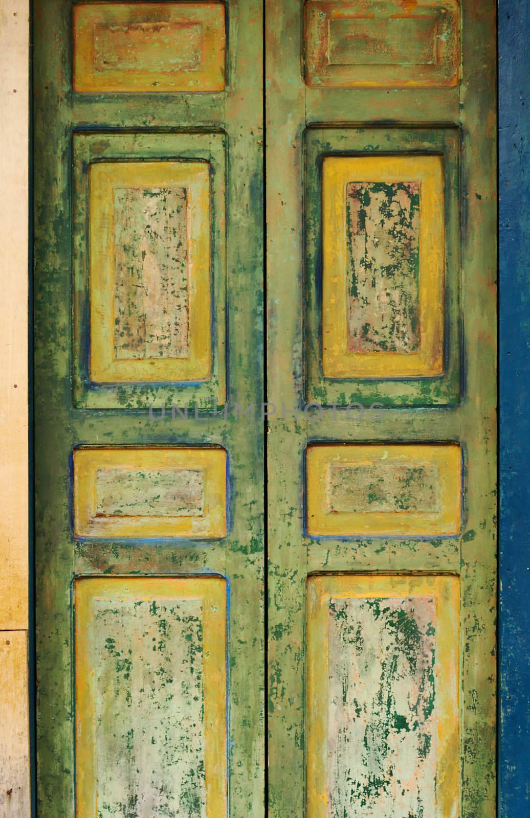 Old wooden door with fading green and yellow painting