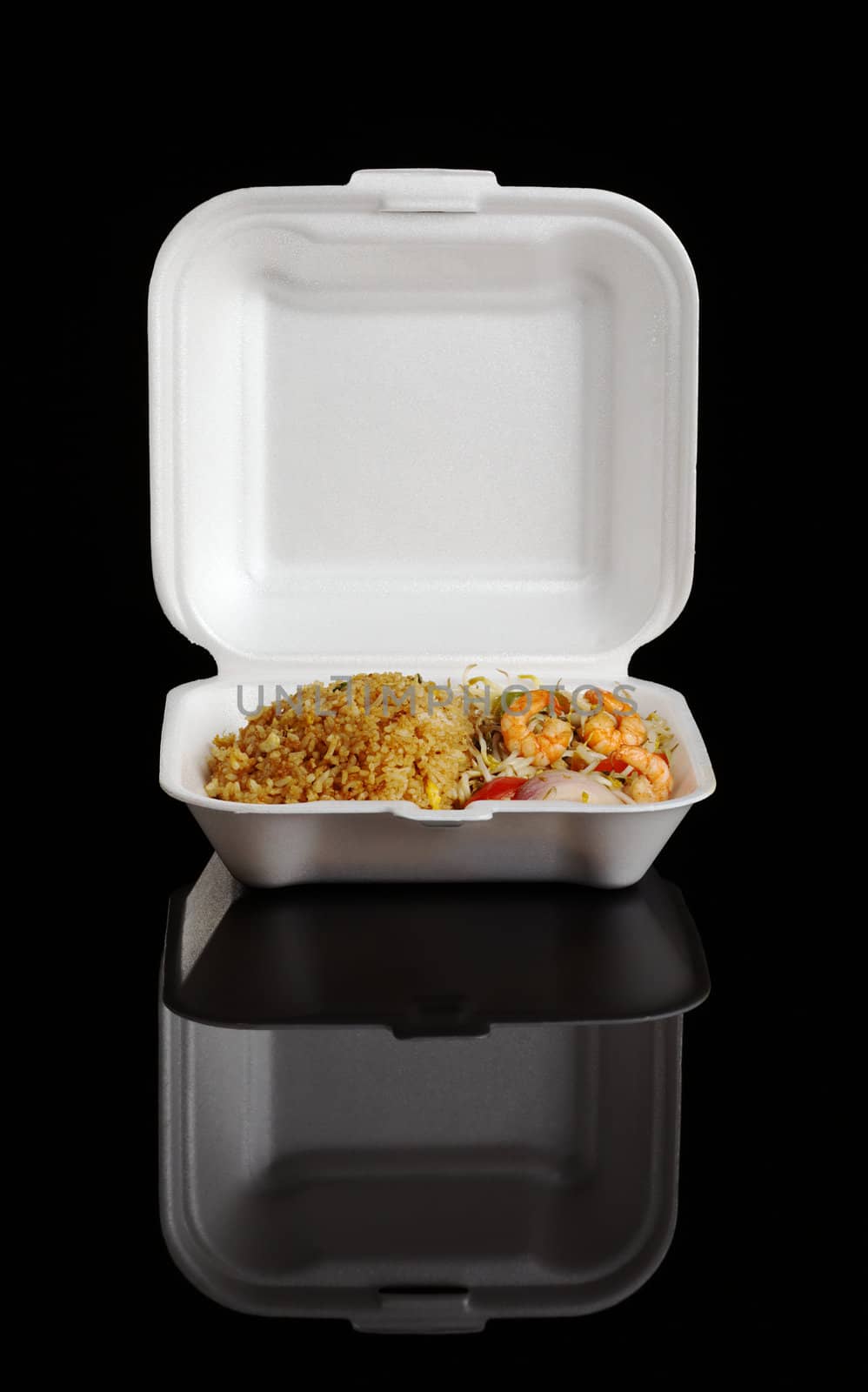 Chinese take-away food: Fried rice with king prawns and vegetables in a styrofoam box photographed on black 