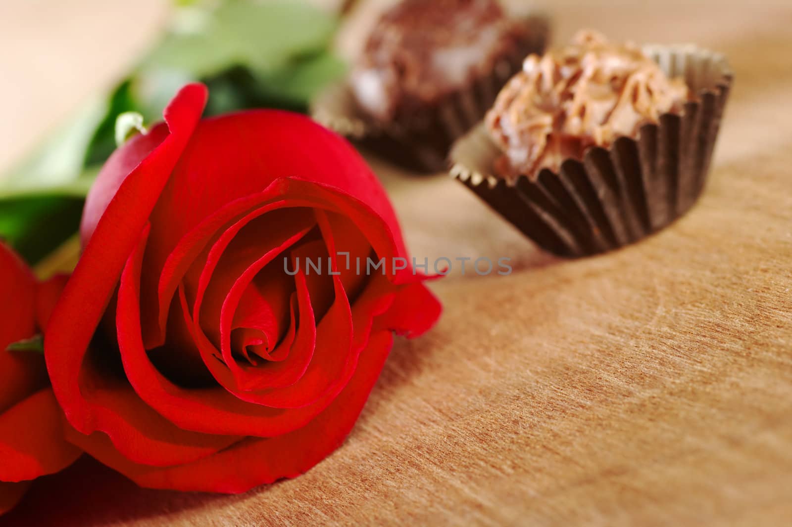 Red rose with two truffles on wooden board (Selective Focus, Focus on the front of the rose)