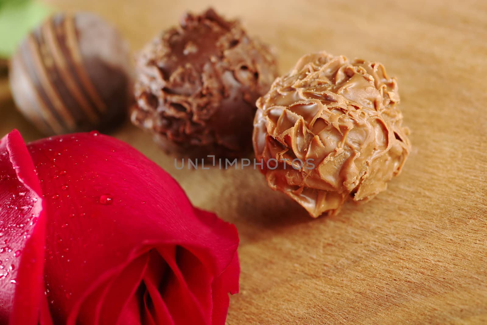 Truffles with a red rose on wooden board (Very Shallow Depth of Field, Focus on the front of the first truffle)