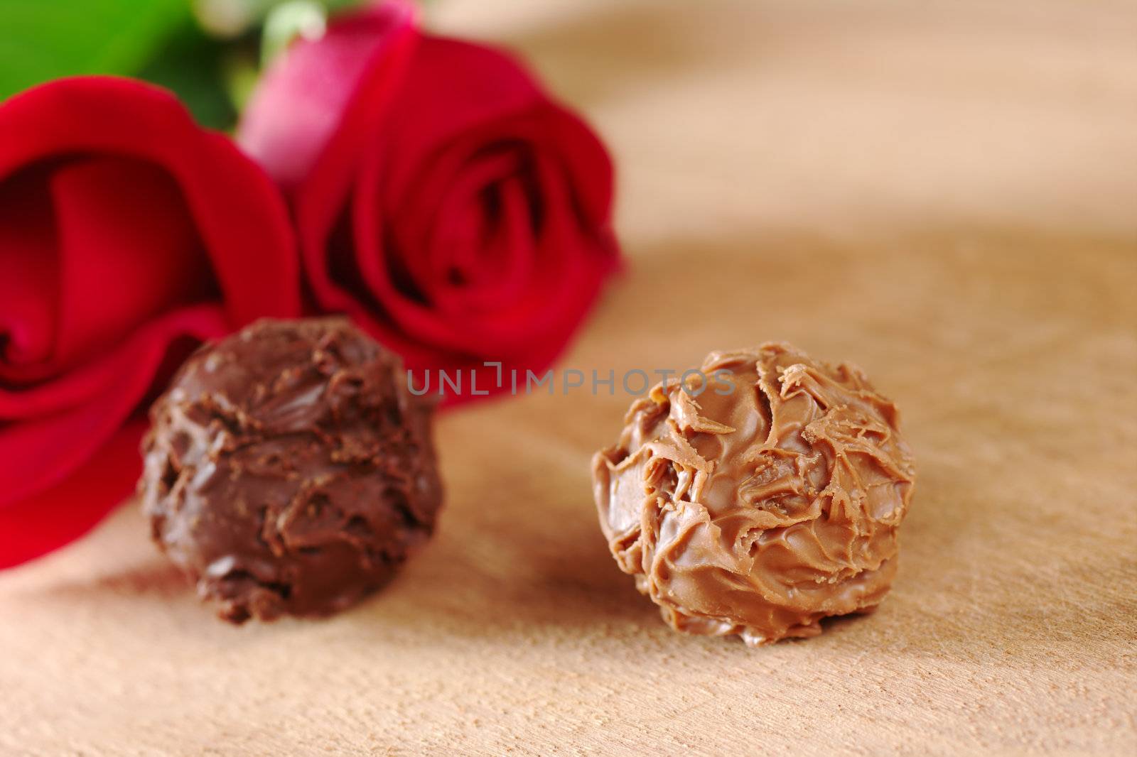 Truffles with red roses on wooden board (Very Shallow Depth of Field, Focus on the front of the right truffle)