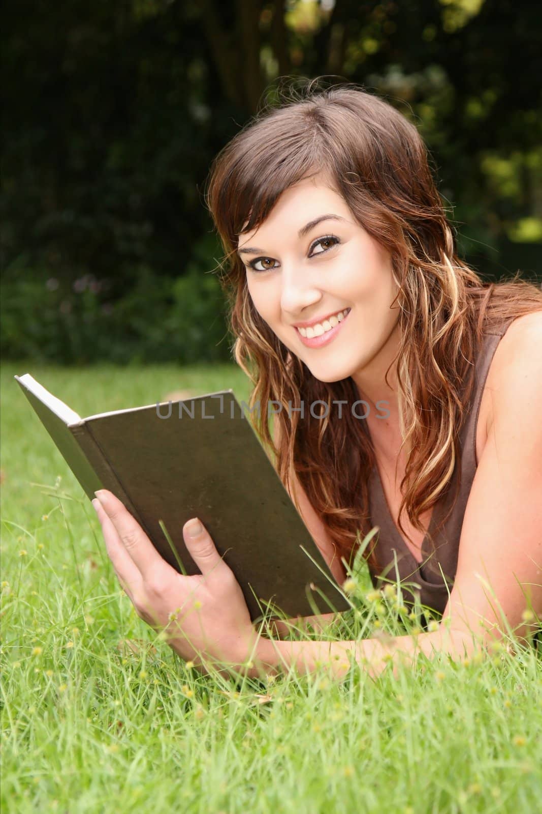 Beautiful young brunette woman reading a book outdoors