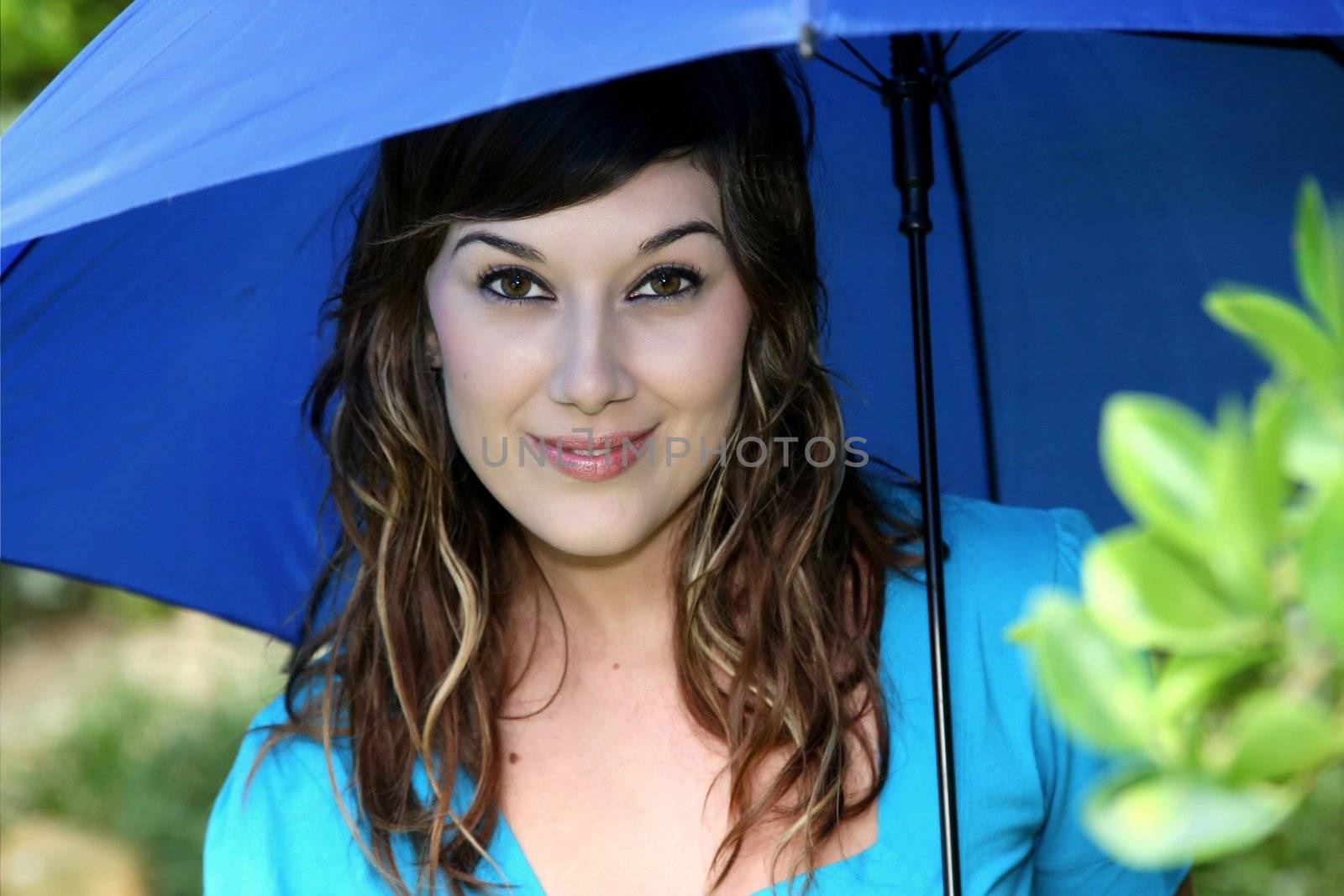 Beautiful smiling young brunette woman with a blue umbrella