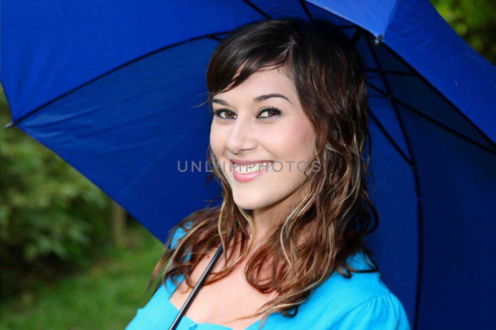 Pretty young brunette lady under a blue umbrella