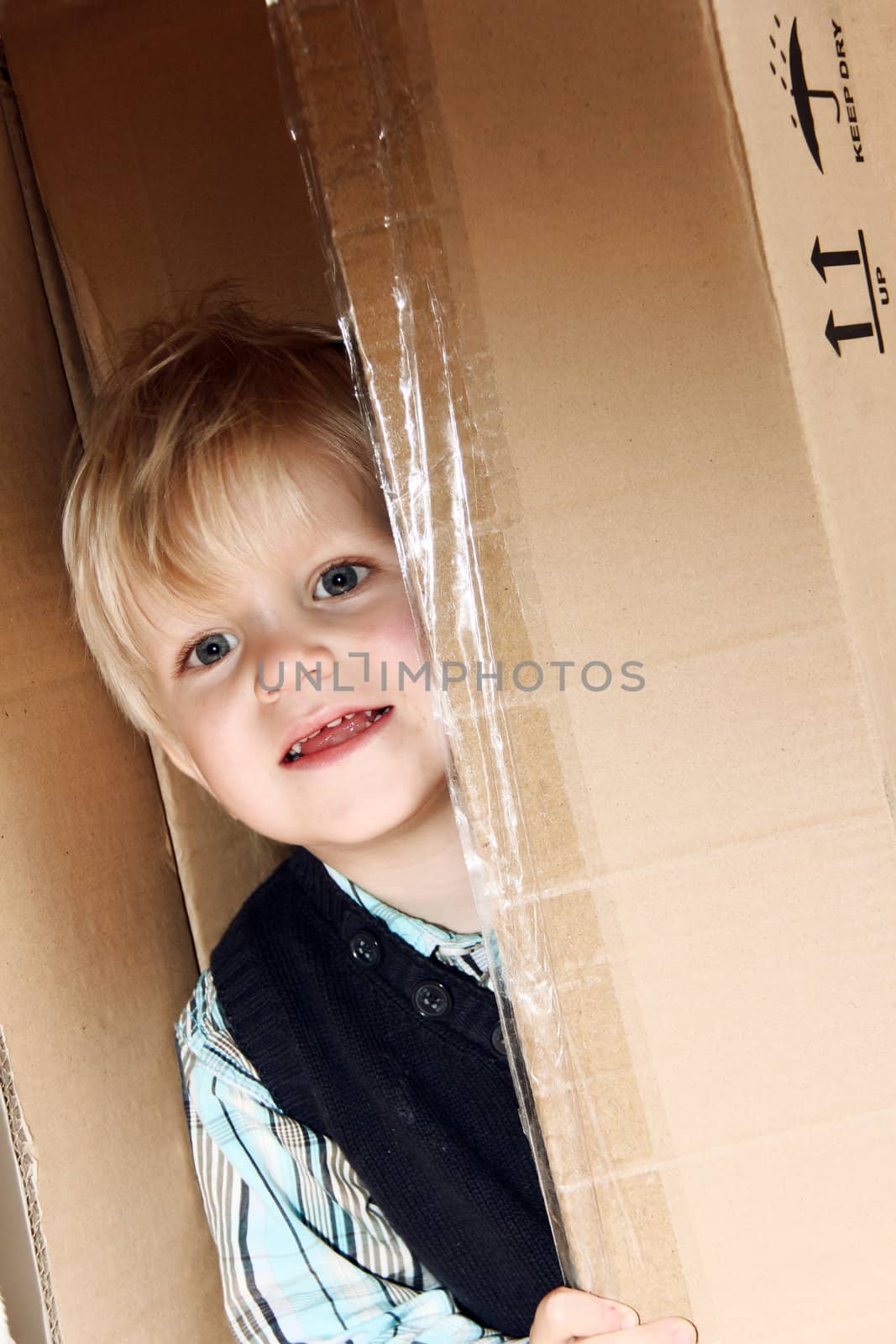 little boy is standing in the brown box alone