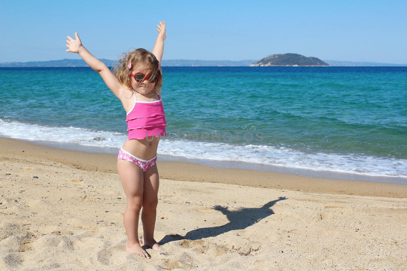 happy young girl with hands up on the beach by goce