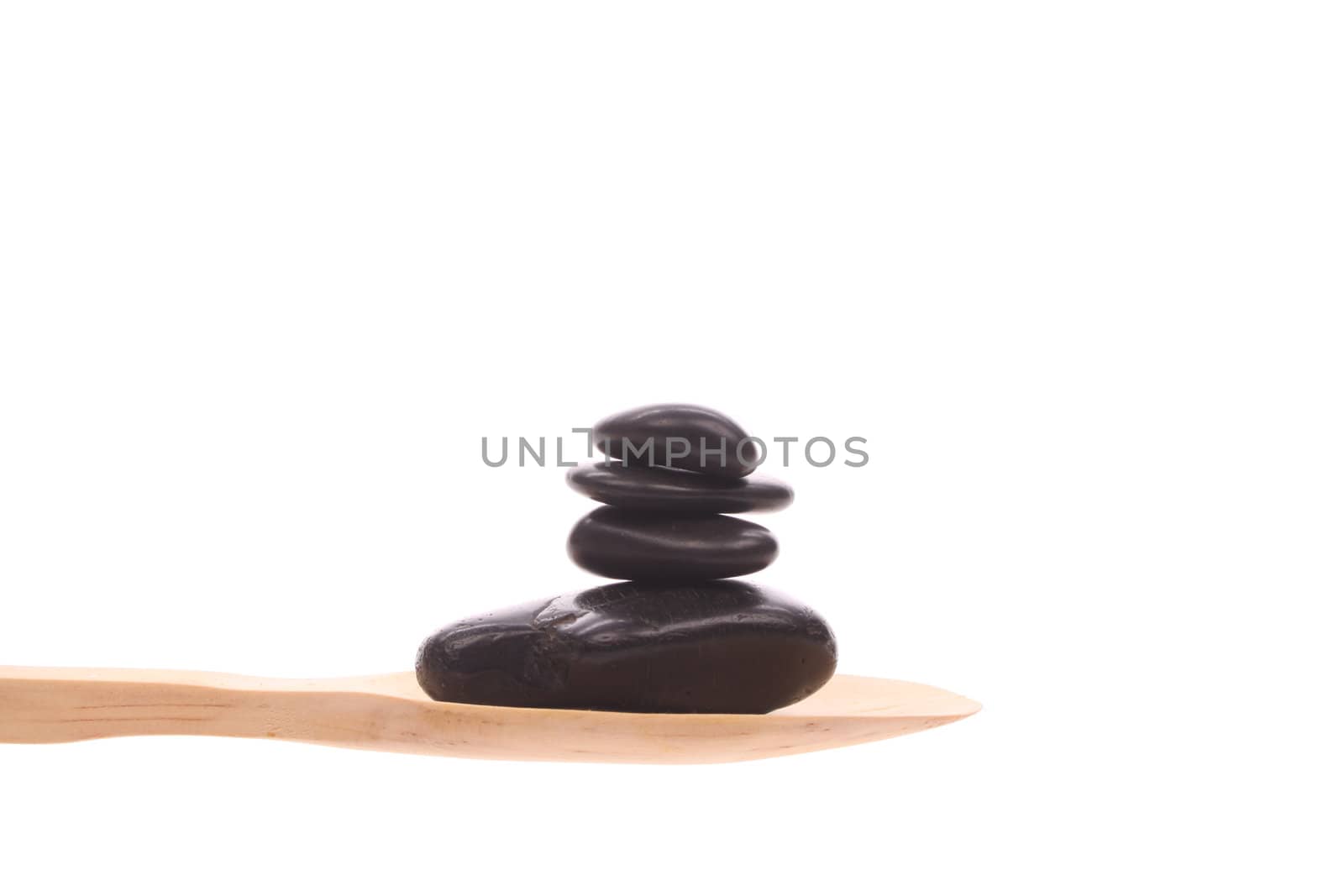 Massage-stone simply offered on a wooden spoon isolated on a white background 