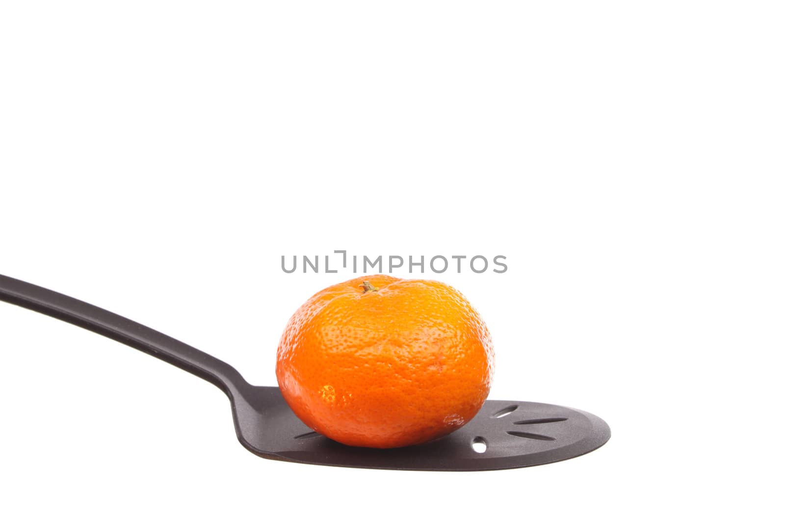 Tangerine on a spoon against a white background