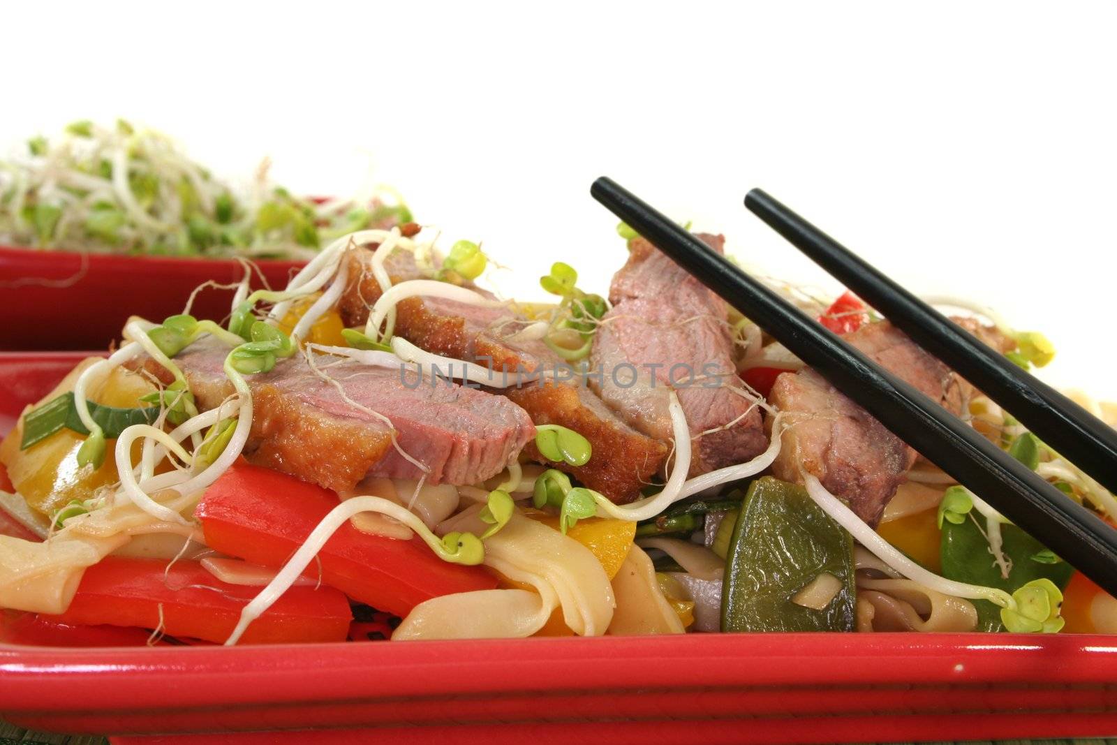 Duck breast with fried noodles, fresh vegetables and radish sprouts