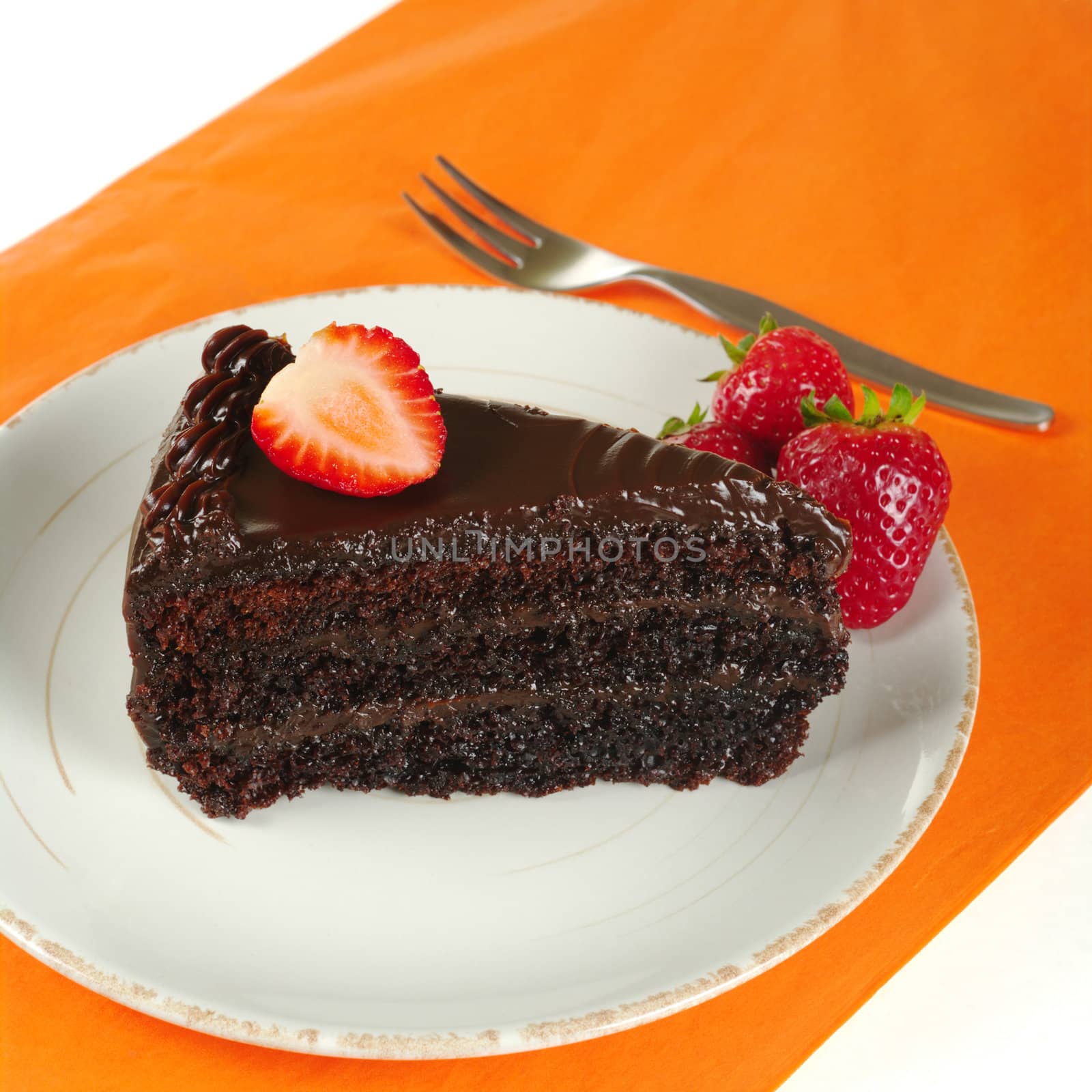 Chocolate cake with strawberries on orange mat with fork (Selective Focus)