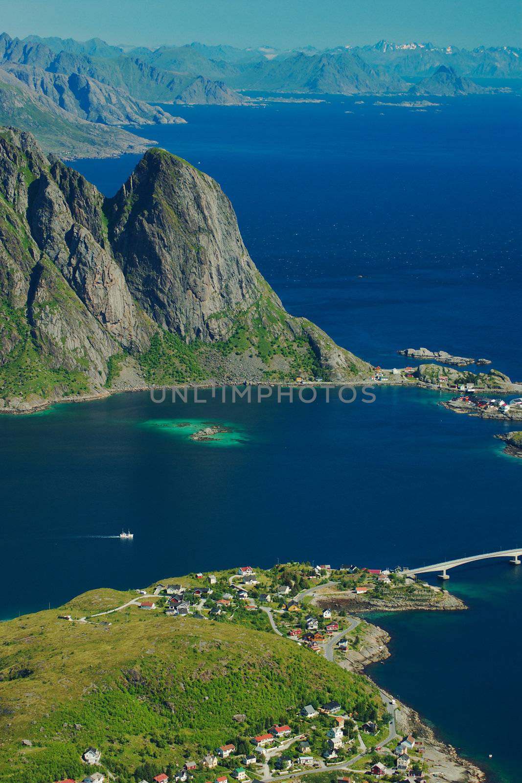 The little town of Reine on the Norwegian island group called Lofoten, which rugged mountain scenery is visible in the background. The picture was taken from a hiking trail to a nearby mountain peak.