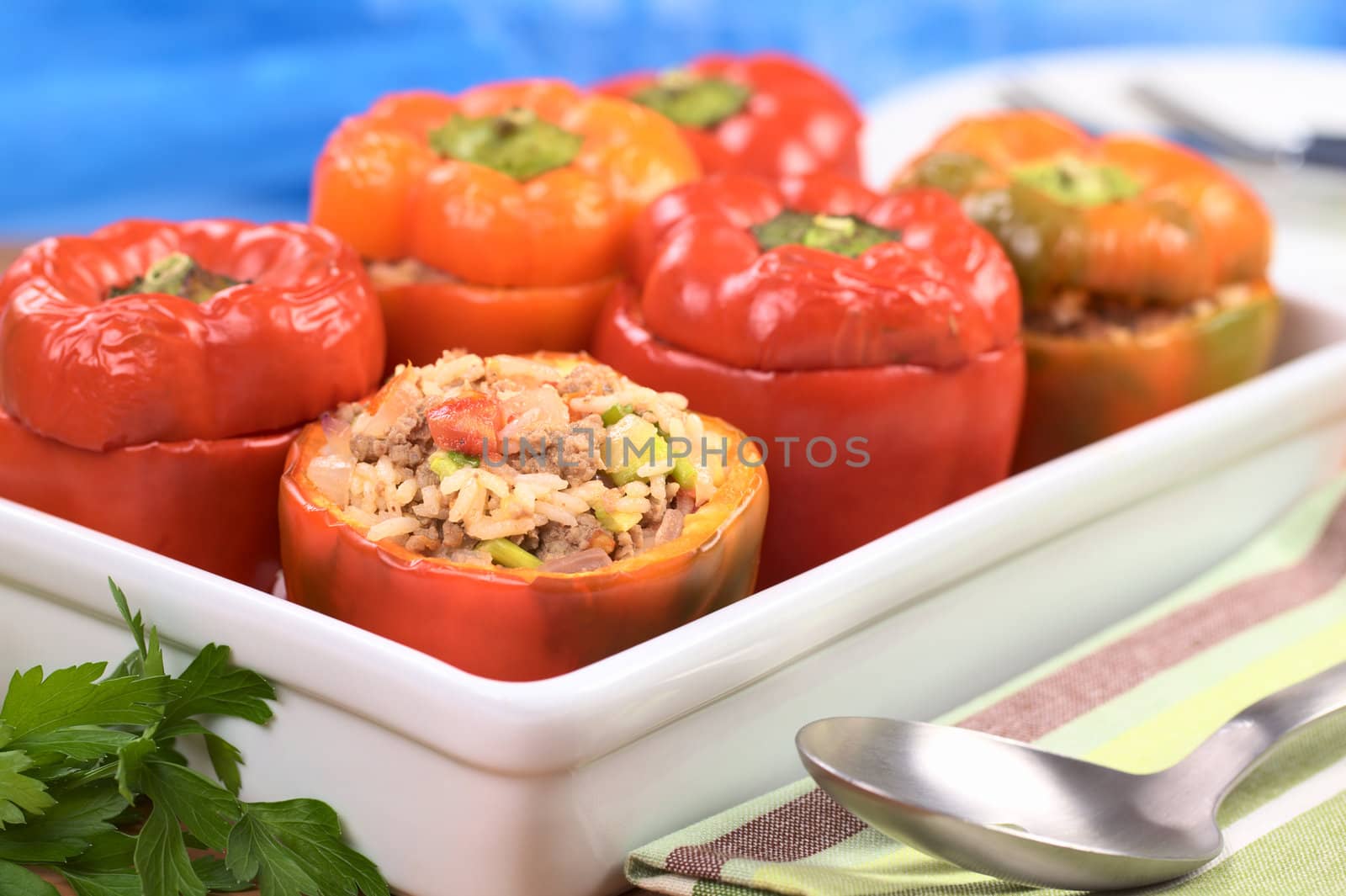 Baked stuffed red bell pepper filled with minced meat, onion, rice, tomato and green onion in a casserole (Selective Focus, Focus on the front of the stuffing)