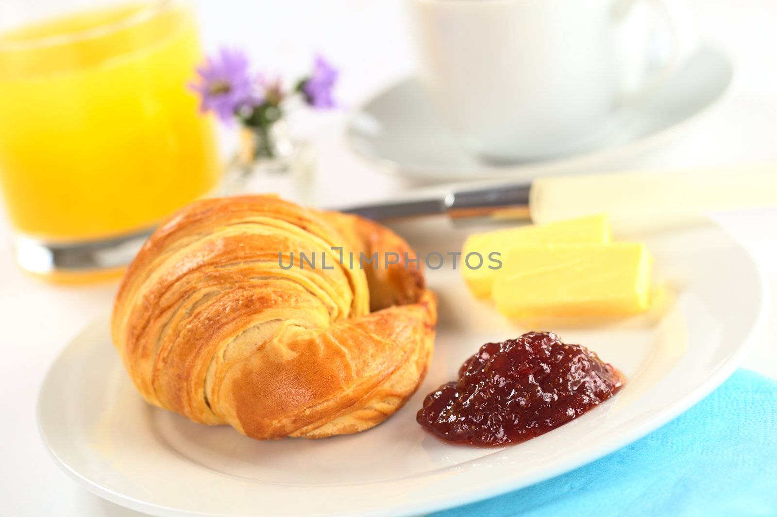 Continental breakfast with croissant, strawberry jam, butter, orange juice and coffee (Selective Focus, Focus on the jam)