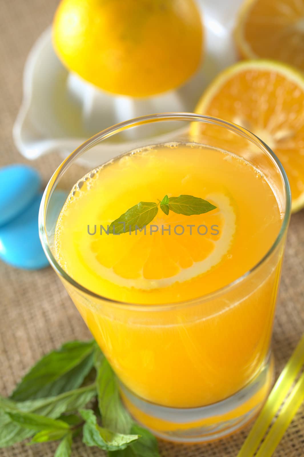 Freshly squeezed orange juice with orange slice and mint on top of the juice (Selective Focus, Focus on the mint leaf on the juice)