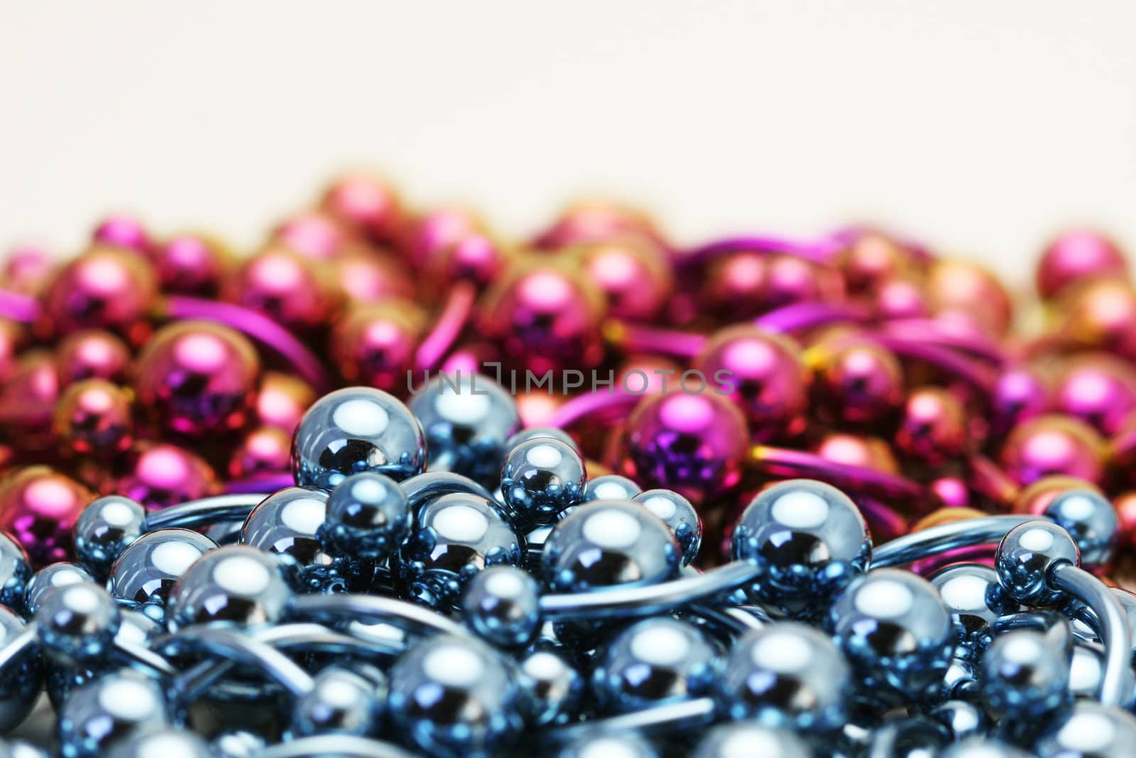 A bulk pile of titanium anodized navel belly rings sitting on a white background