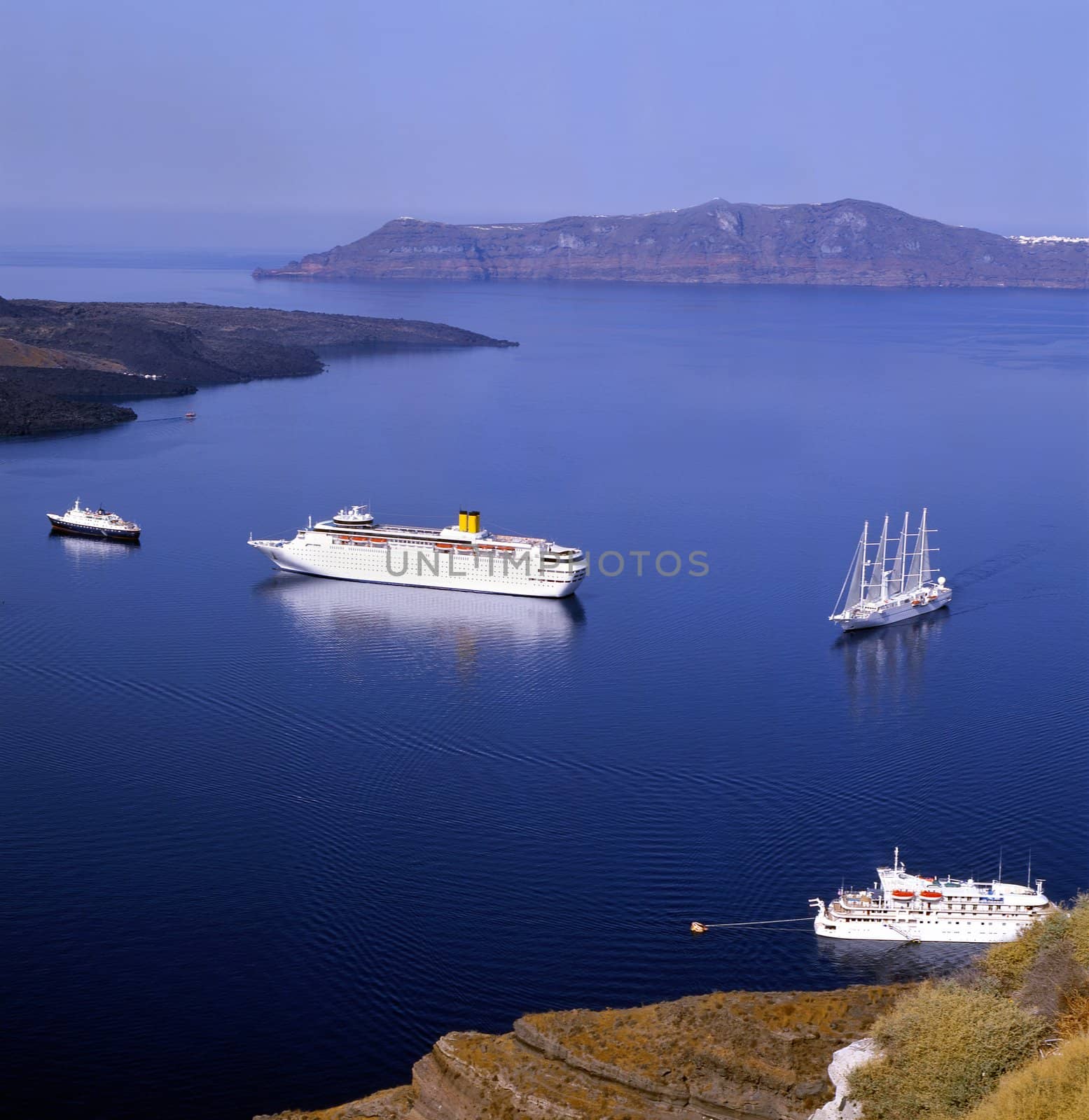 Sailboats at the entrance to Santorini harbour in blue calm sea, greece, europe