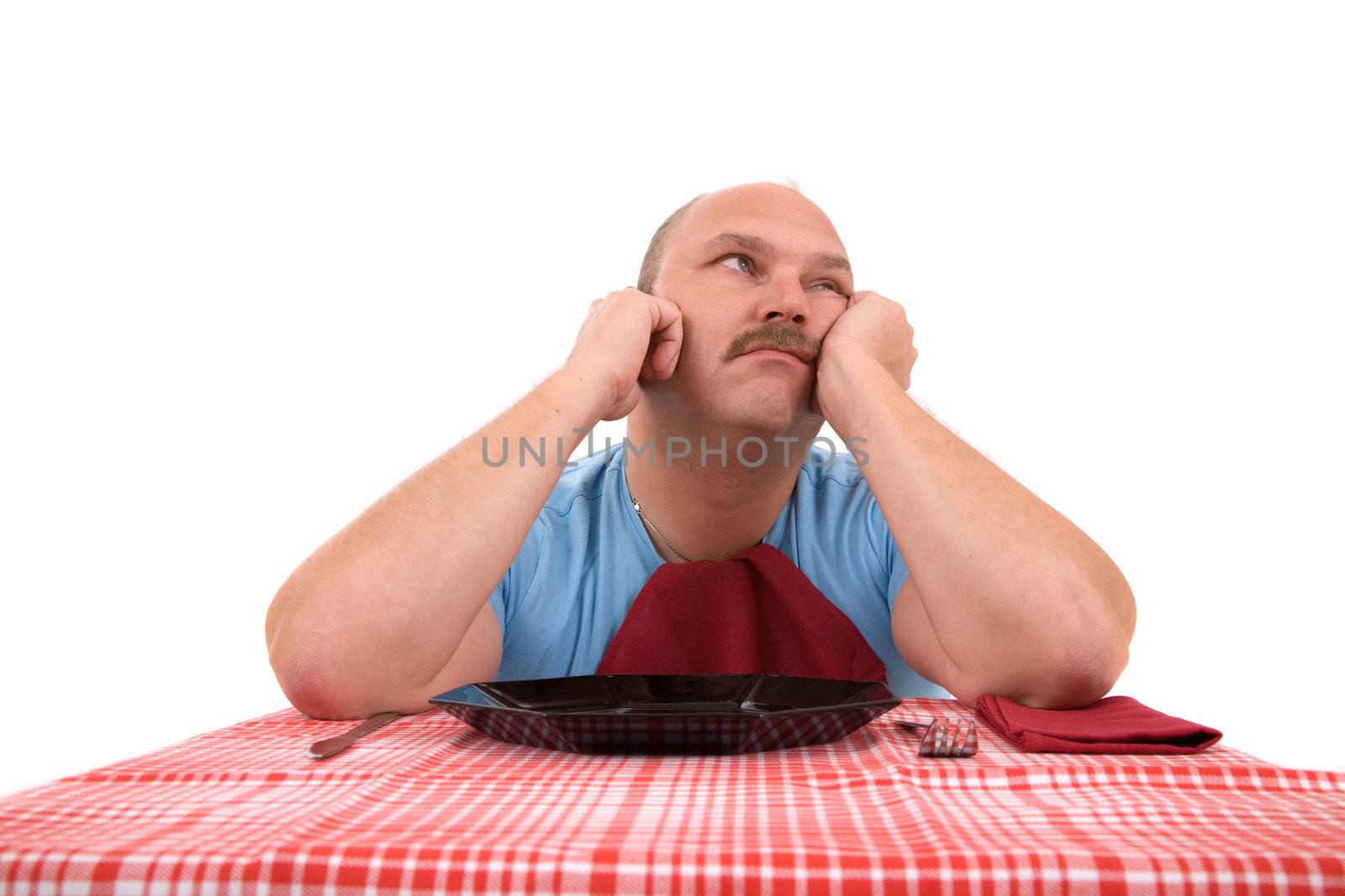 Overweight man looking very unhappy with empty plate in front of him