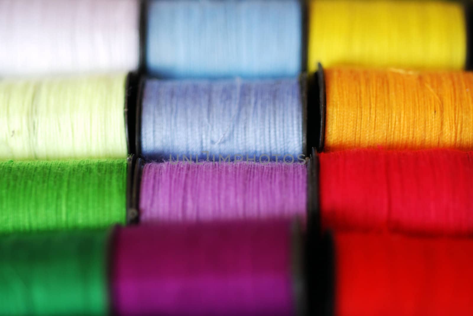 Colourful spools of bright cotton thread, in macro