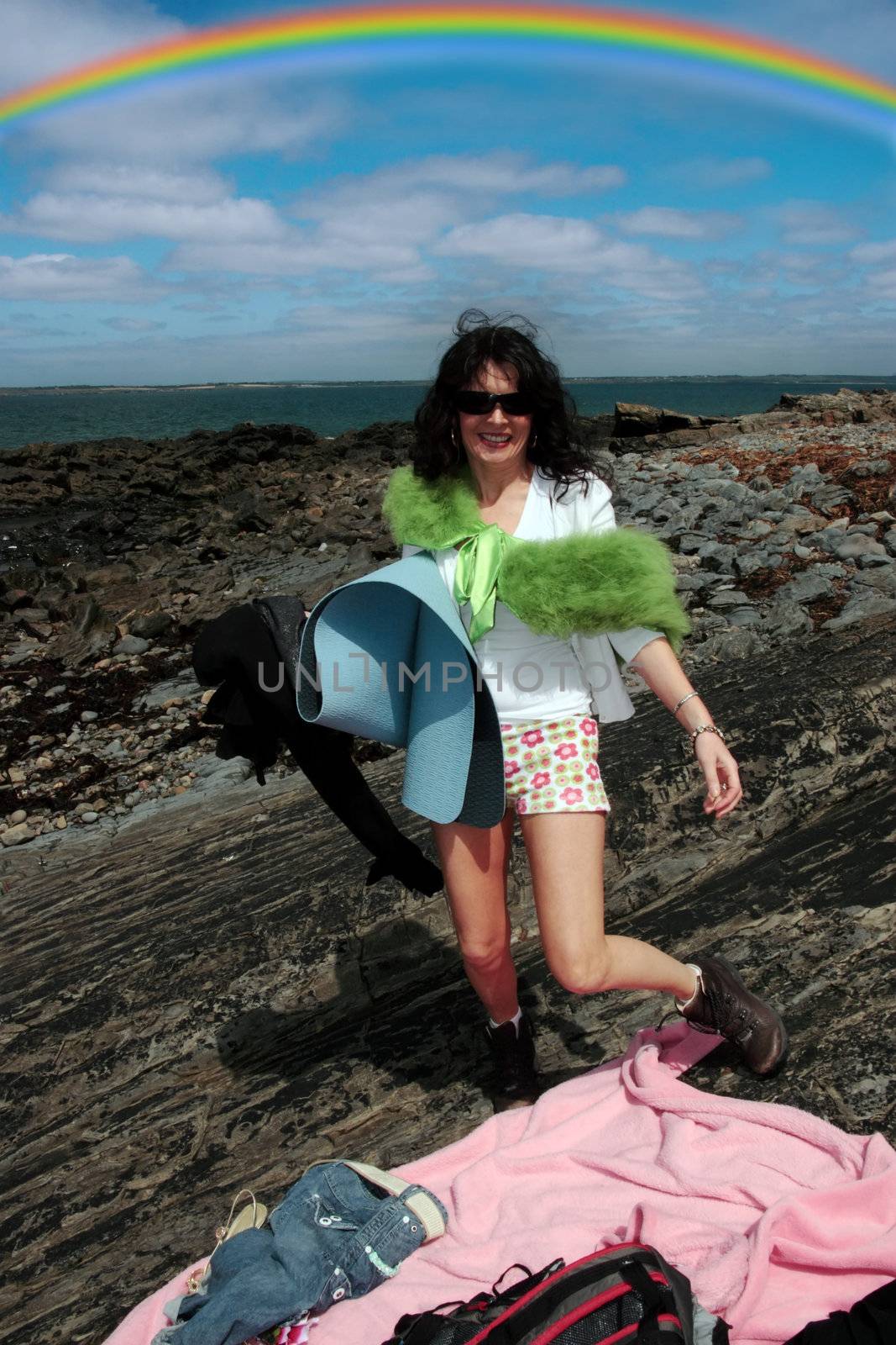 a woman ready to enjoy a day of freedom on the beach with a rainbow behind her