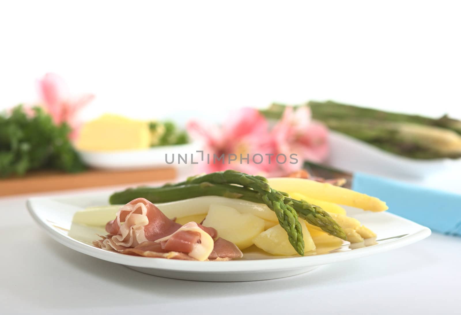 Green and white asparagus on potatoes with ham in the foreground (Very Shallow Depth of Field, Focus on the tip of the asparagus in front)