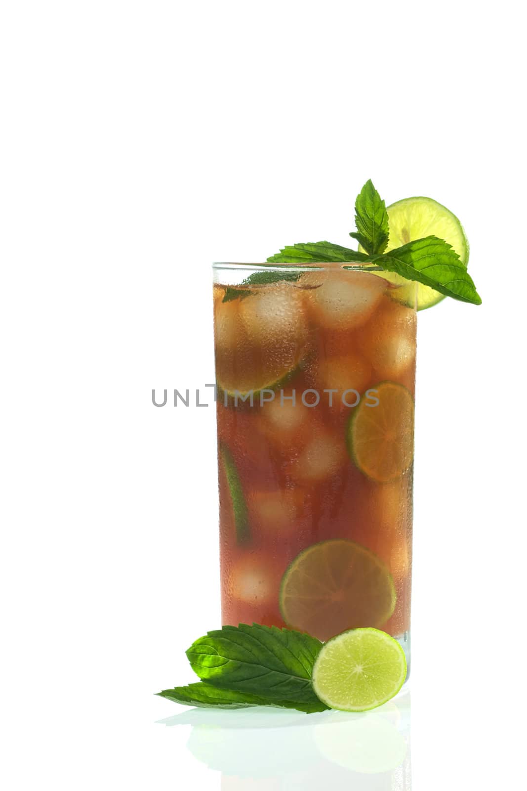Refreshing iced tea out of black tea, ice cubes, lime slices, garnished with fresh mint leaves and lime slices 