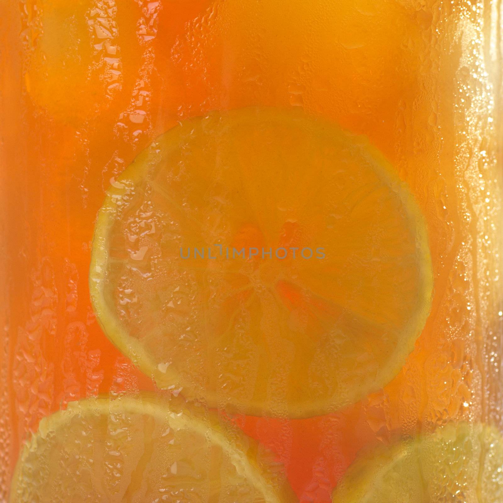 Iced tea as background with lime slices and ice cubes in glass with water drops on the glass 