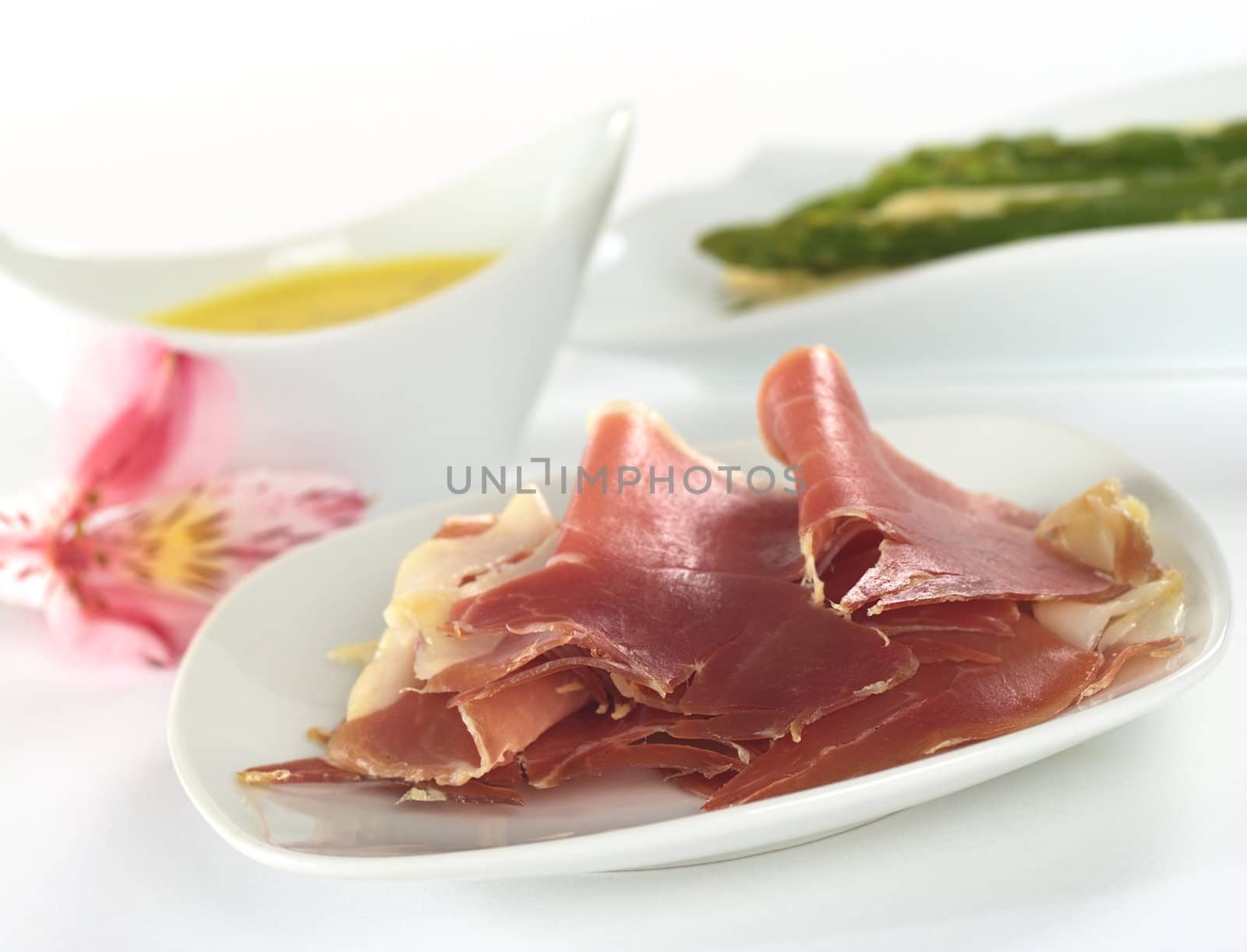 Thin ham slices with asparagus and Hollandaise sauce in the back (Selective Focus, Focus on the front of the ham)