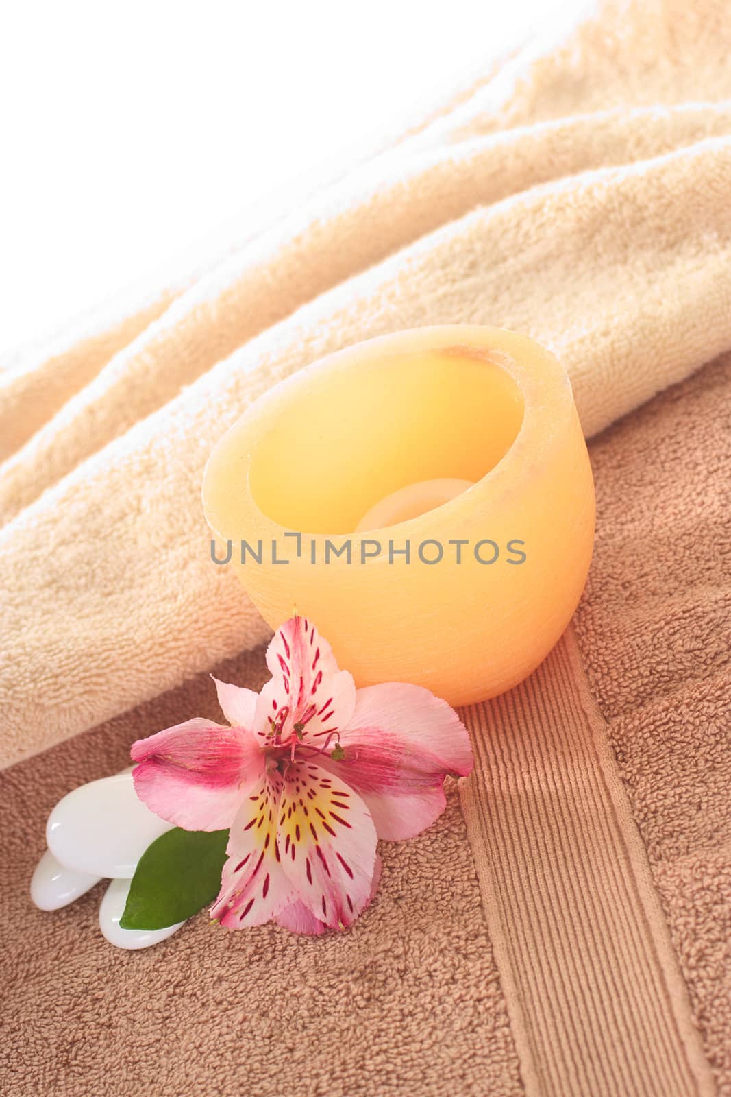 Spa still life with Inca Lily and candle on towel (Selective Focus, Focus on the front of the candle and the flower)