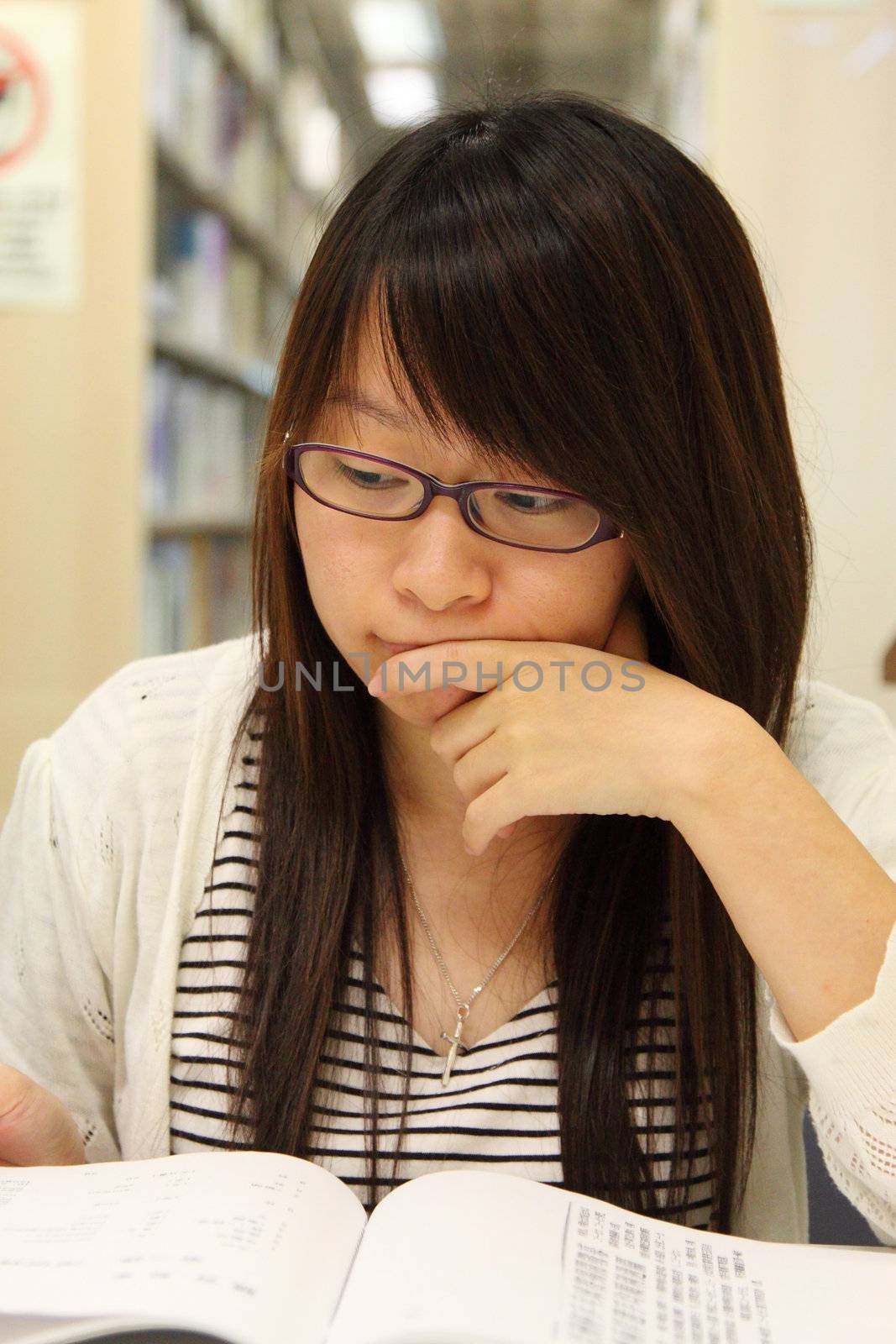 Asian girl student in library, she is studying very hard.