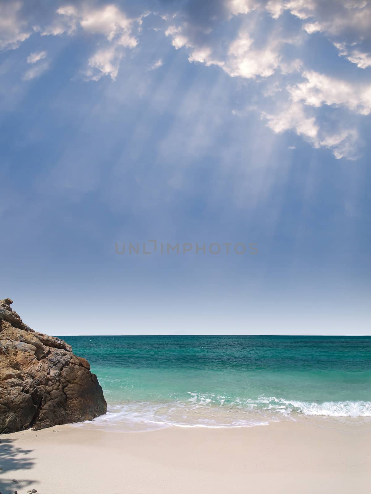 Summer paradise view with beautiful beach, emerald color sea and rays from heaven